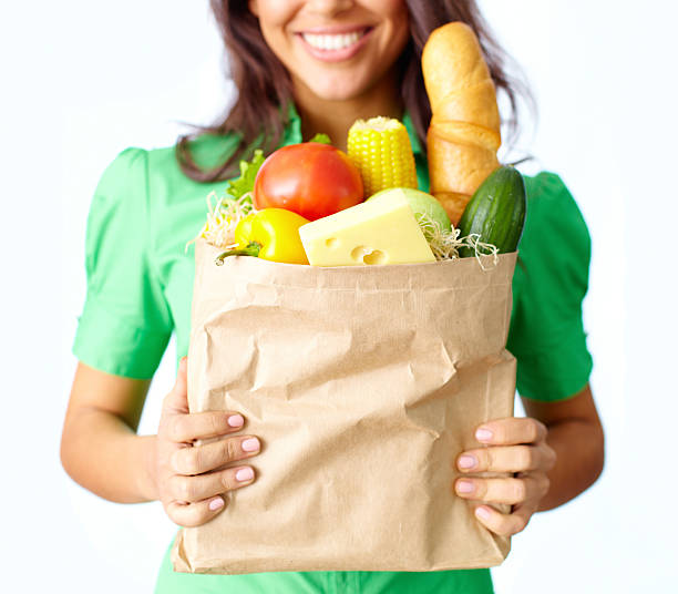 Smiling person holding a bag of fresh groceries